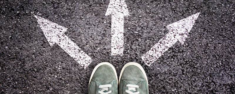 feet on pavement with three arrows showing three different paths to take