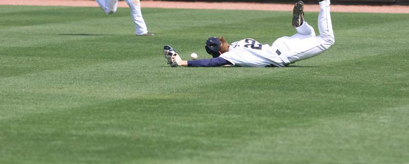 man diving to catch baseball and missing