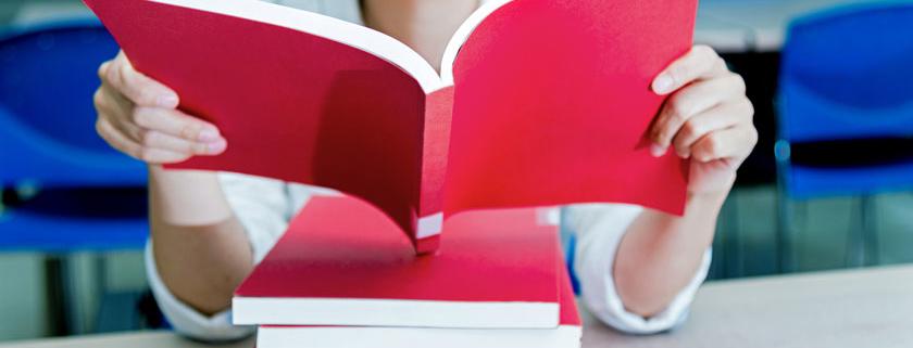 young woman reading a red book on a stack of other red books